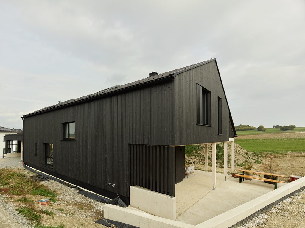 schwarze Hausfassade und gedeckter Sitzplatz